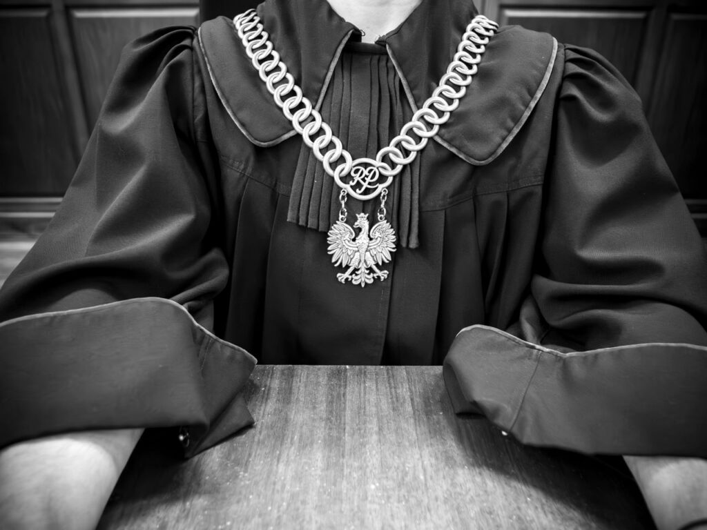Monochrome photo of judge in traditional robes with emblematic necklace.